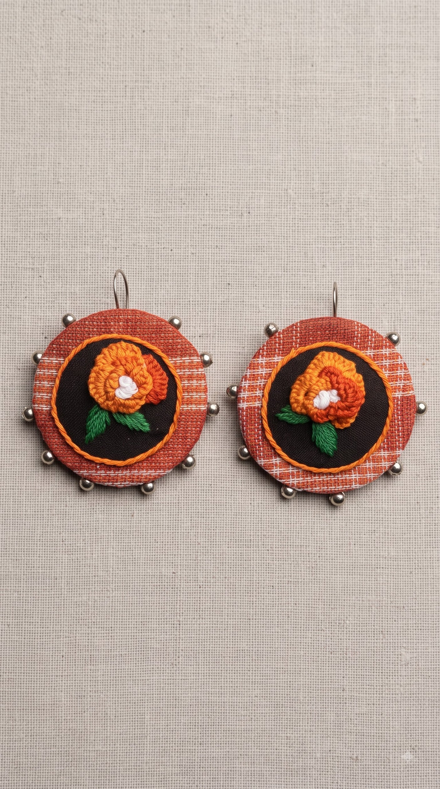 Hand-Embroidered Orange Floral Disc Earrings on Rust Fabric
