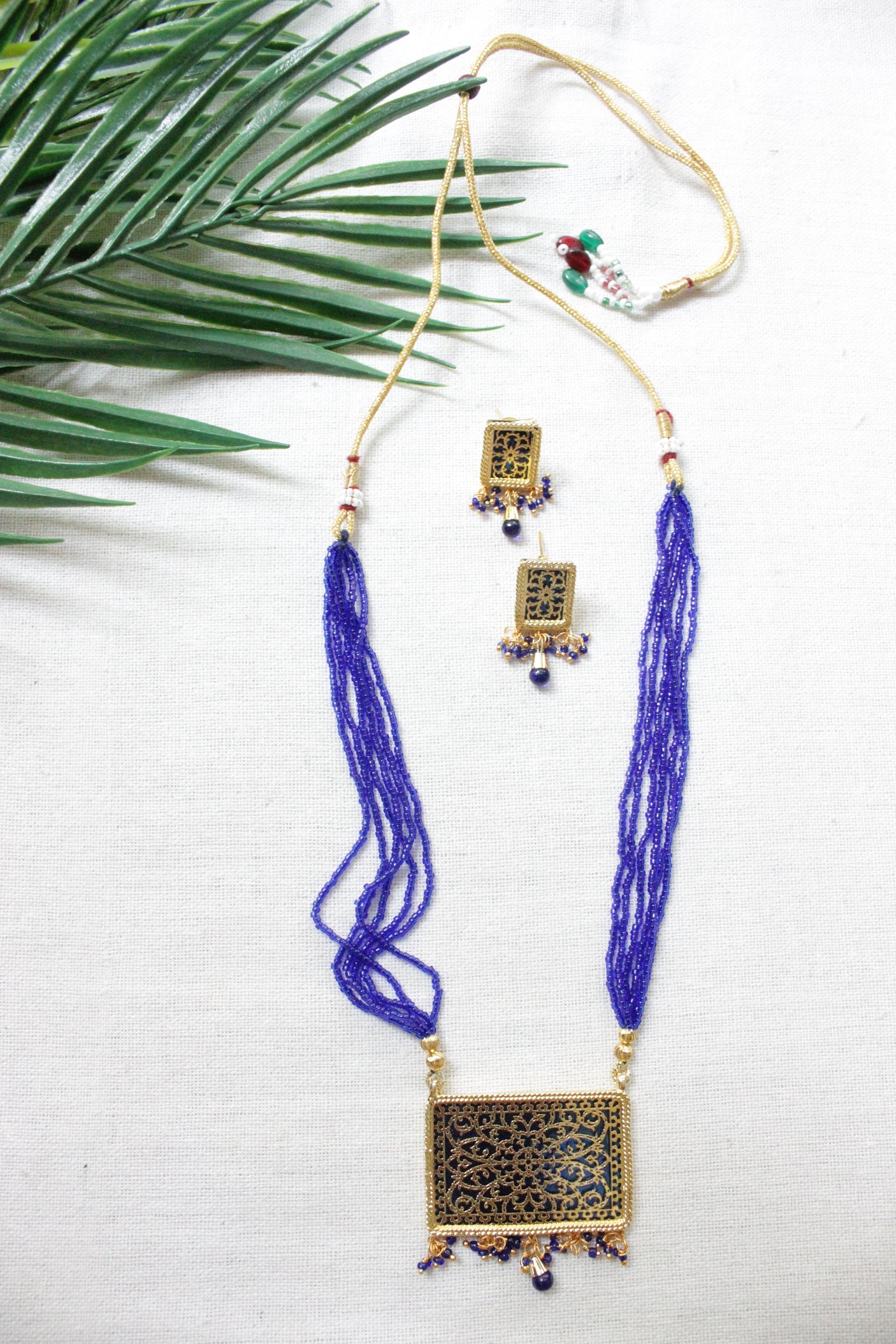 Intricately Detailed Gold Toned Rectangular Pendant Necklace Set with Multi-Layer Blue Beads Closure