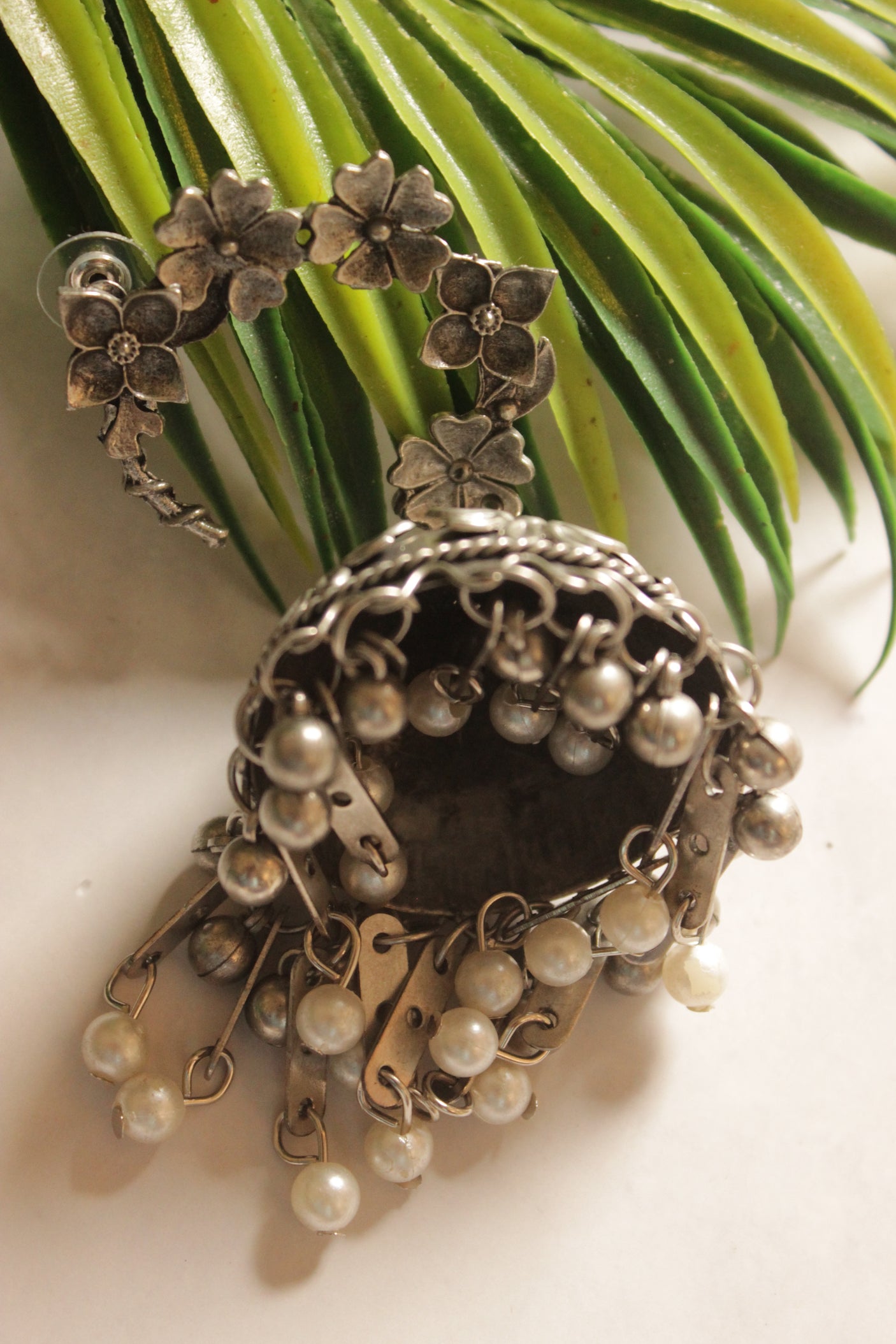 Oxidised Finish Flower Embossed Jhumka Earrings with White Beads