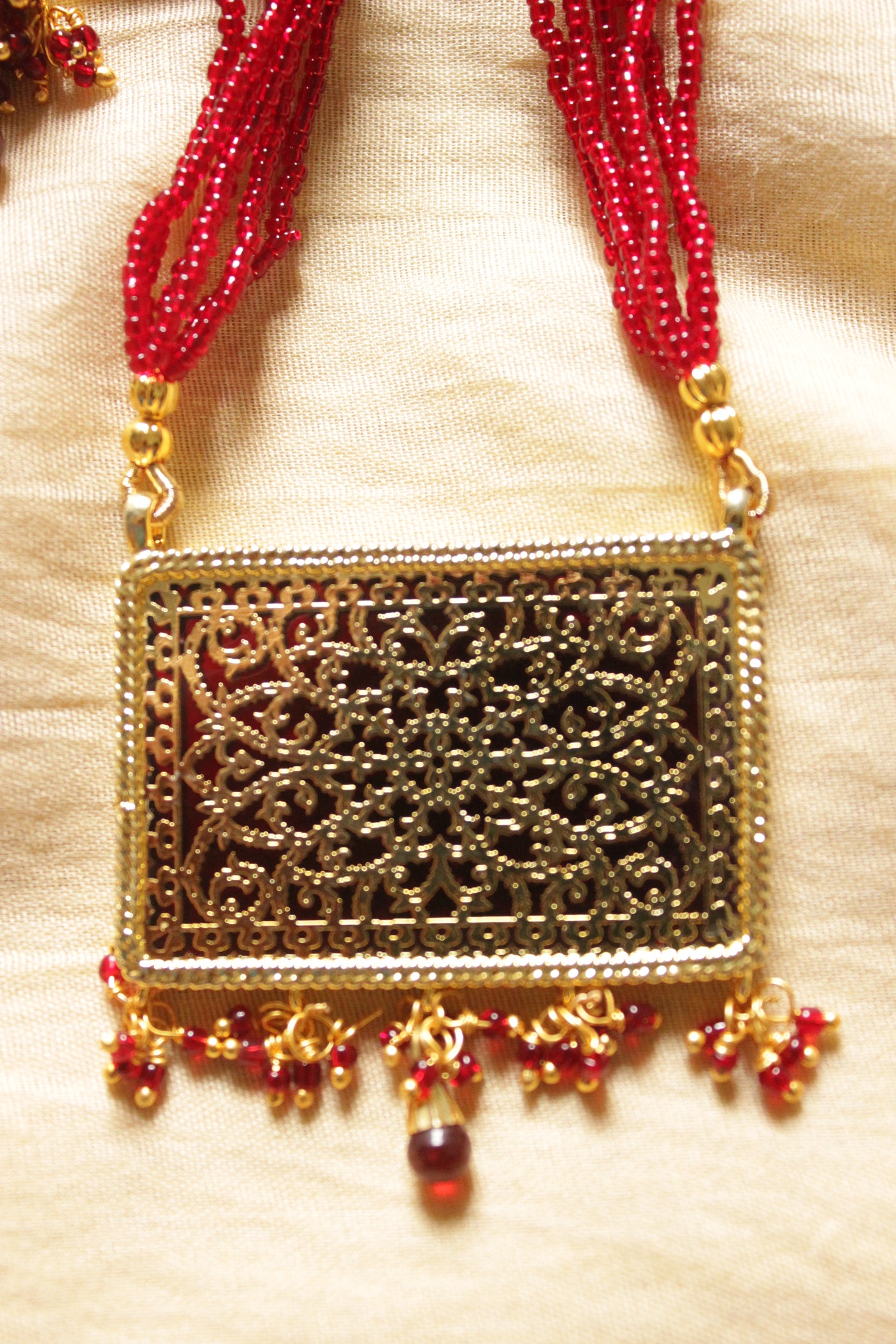 Intricately Detailed Gold Toned Rectangular Pendant Necklace Set with Multi-Layer Red Beads Closure