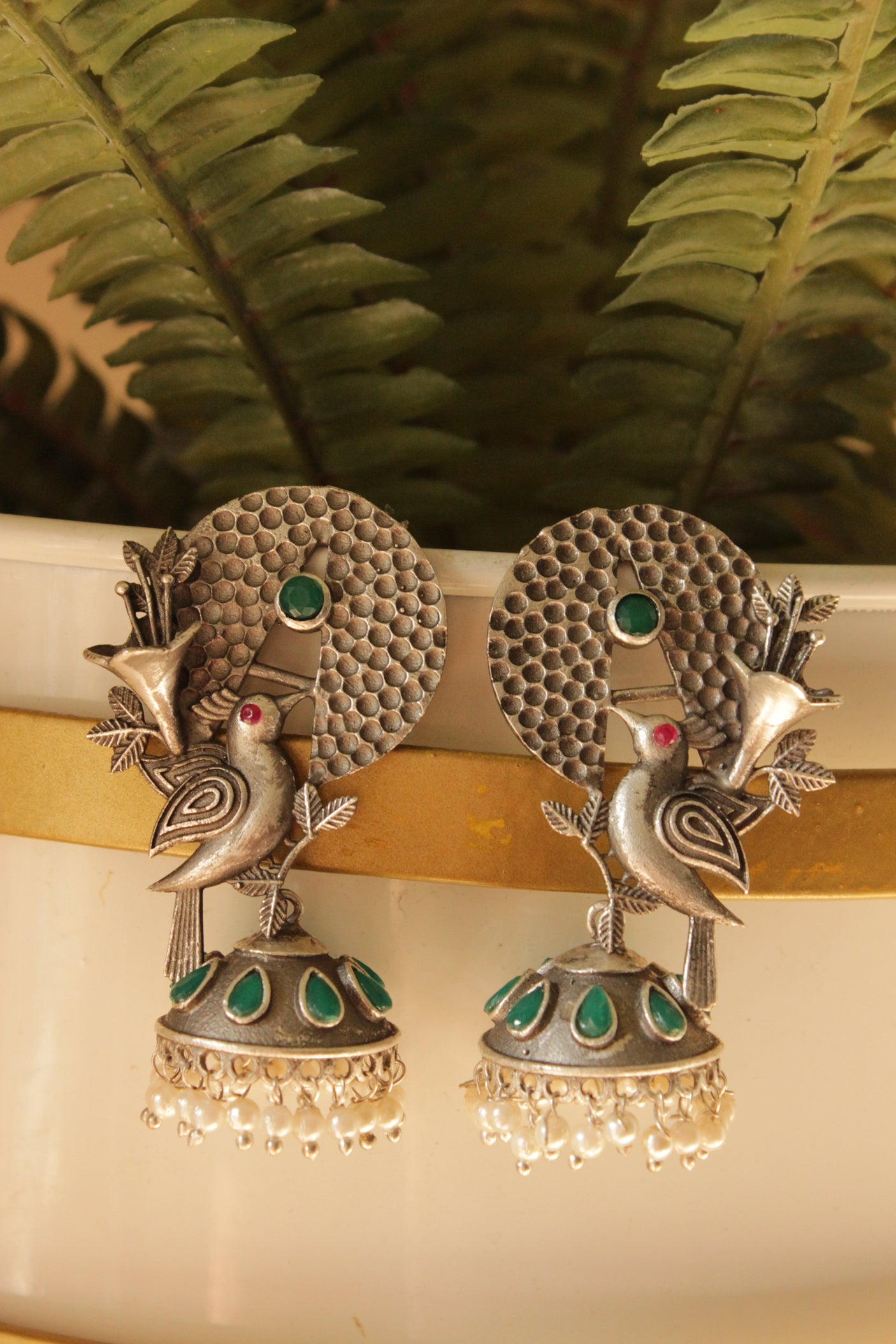 Green Stones Embedded Silver Finish Peacock Motif Statement Dangler Earrings Accentuated with White Beads