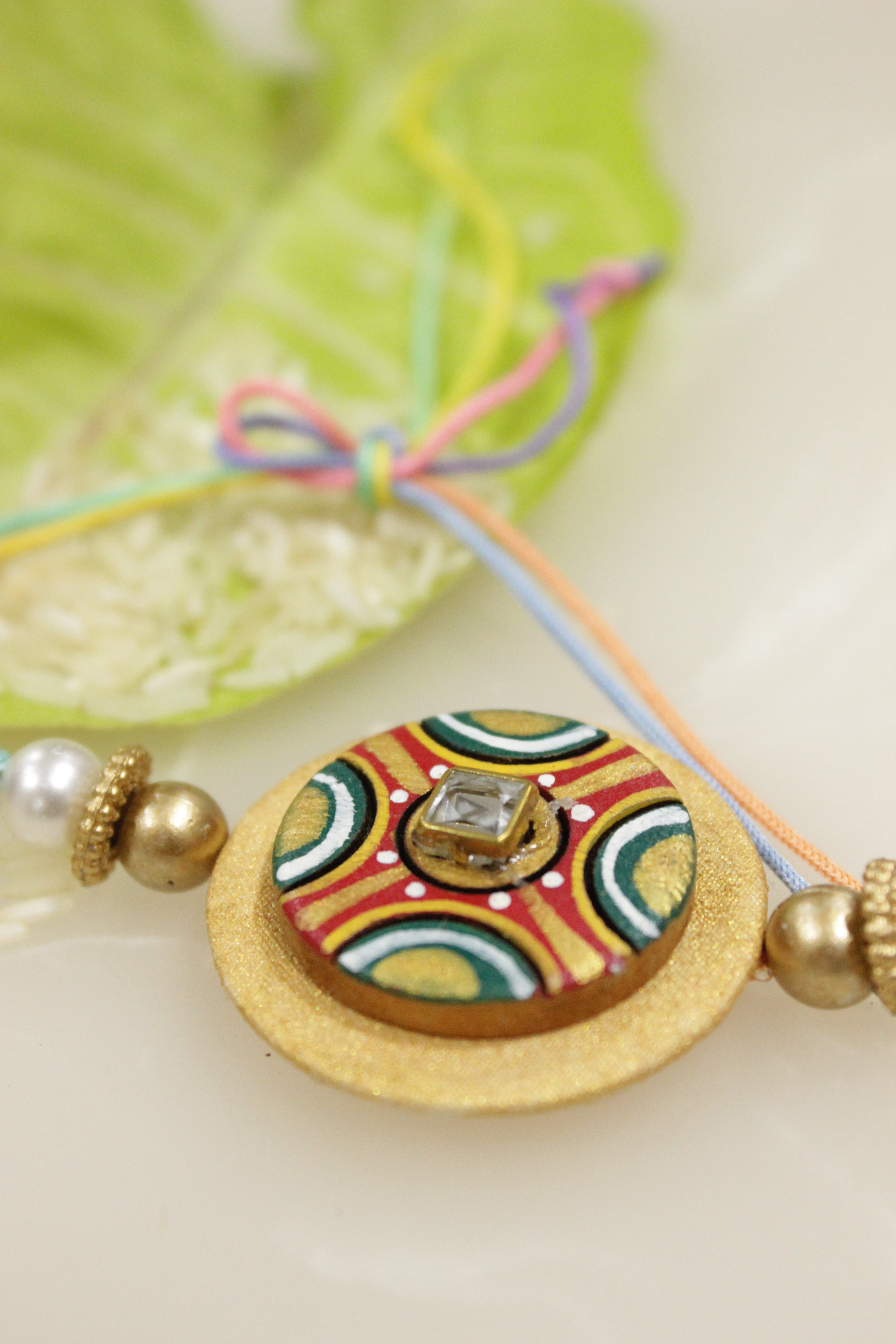 Fabric and Terracotta Clay Golden Hand Painted Rakhi