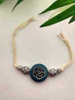 Load image into Gallery viewer, Intricately Detailed Blue Wood and Metal Rakhi with Off-White Cotton Thread
