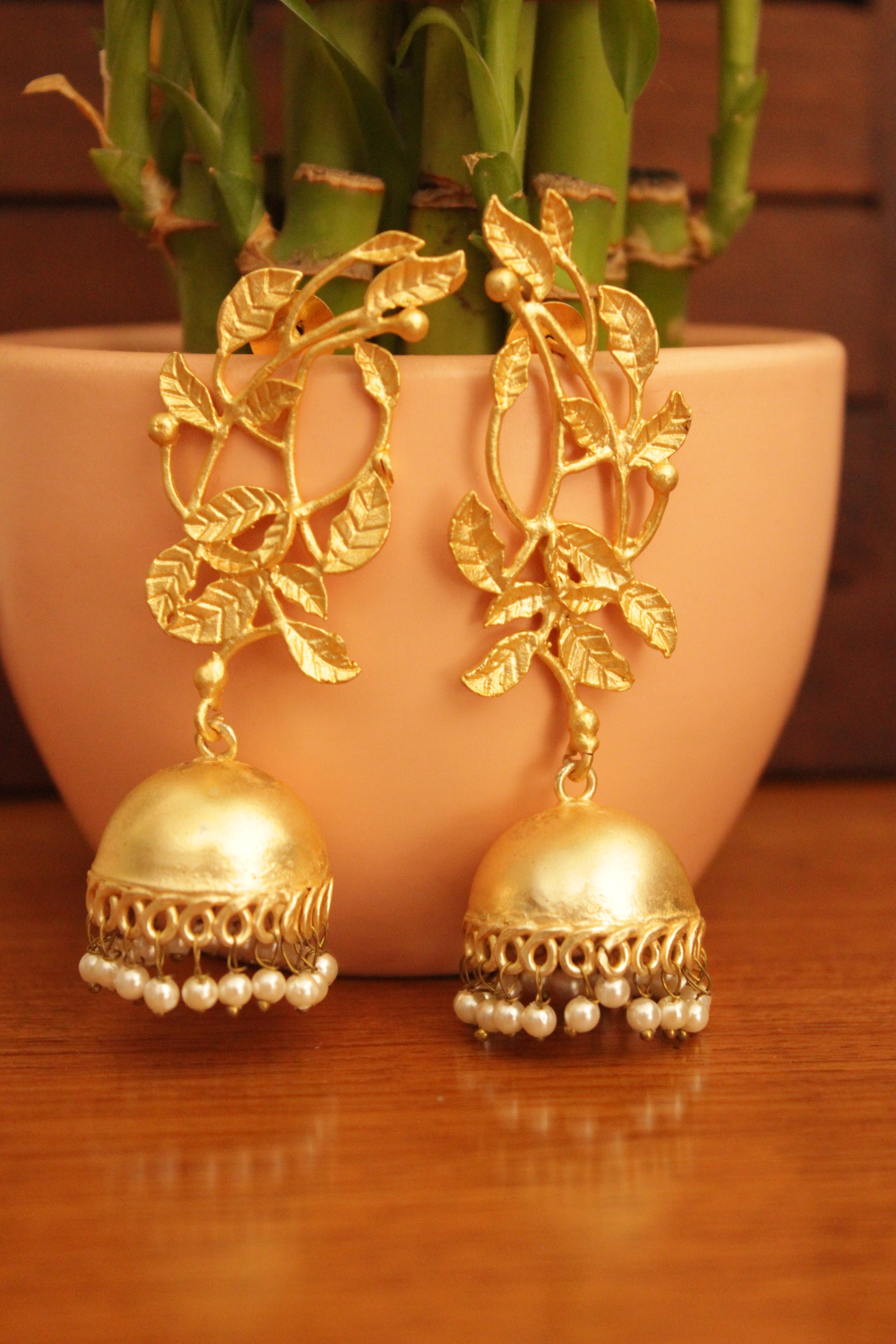 Leaf Motifs Gold Toned Brass Dangler Jhumka Earrings Accentuated with White Beads