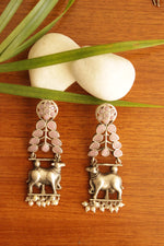 Load image into Gallery viewer, Pink Glass Stones Embedded Cow Motif Oxidised Finish Brass Dangler Earrings
