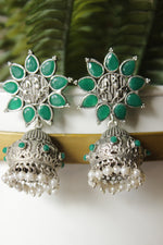 Load image into Gallery viewer, Bottle Green Glass Stones Embedded Silver Finish Flower Motif Dangler Jhumka Earrings in Brass
