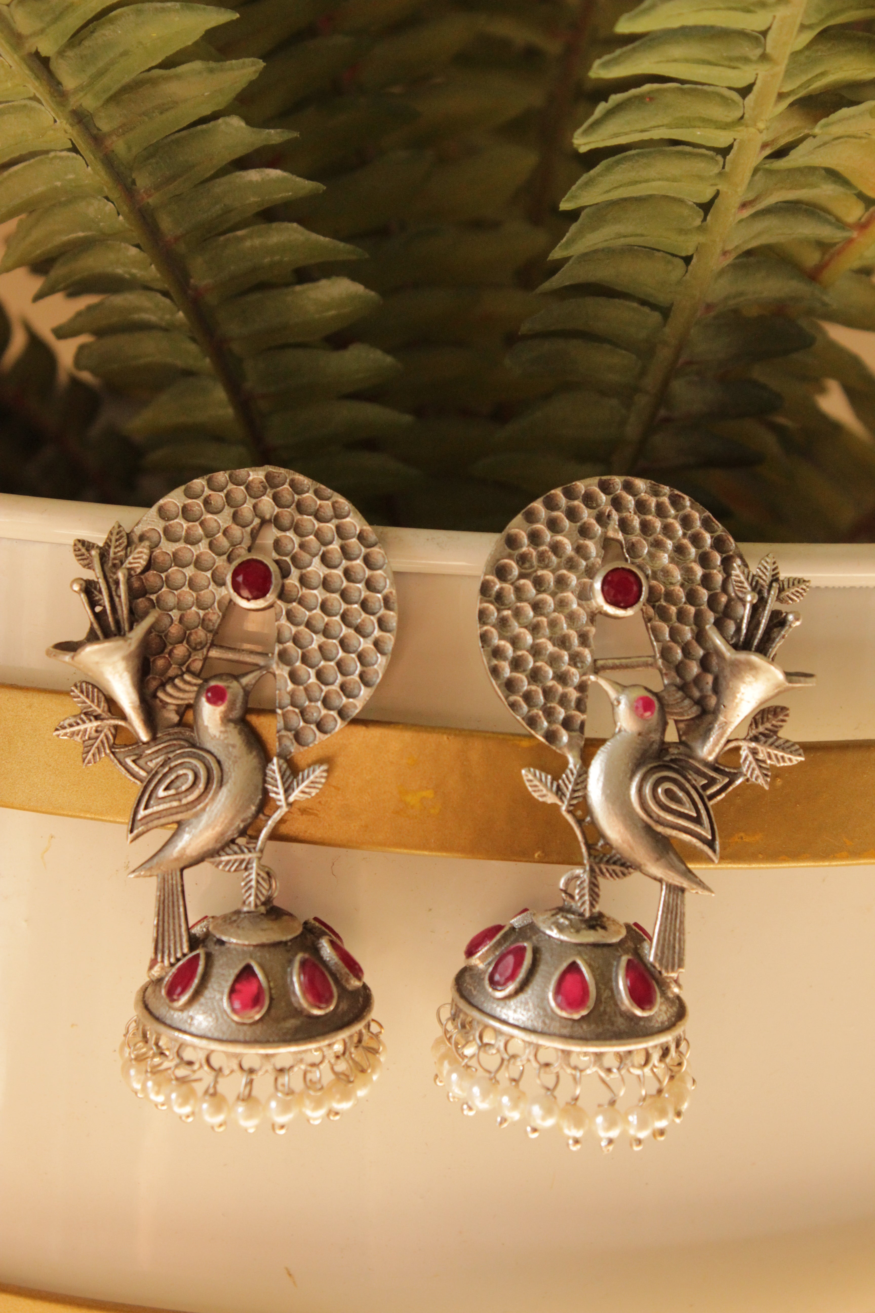 Red Stones Embedded Silver Finish Peacock Motif Statement Dangler Earrings Accentuated with White Beads