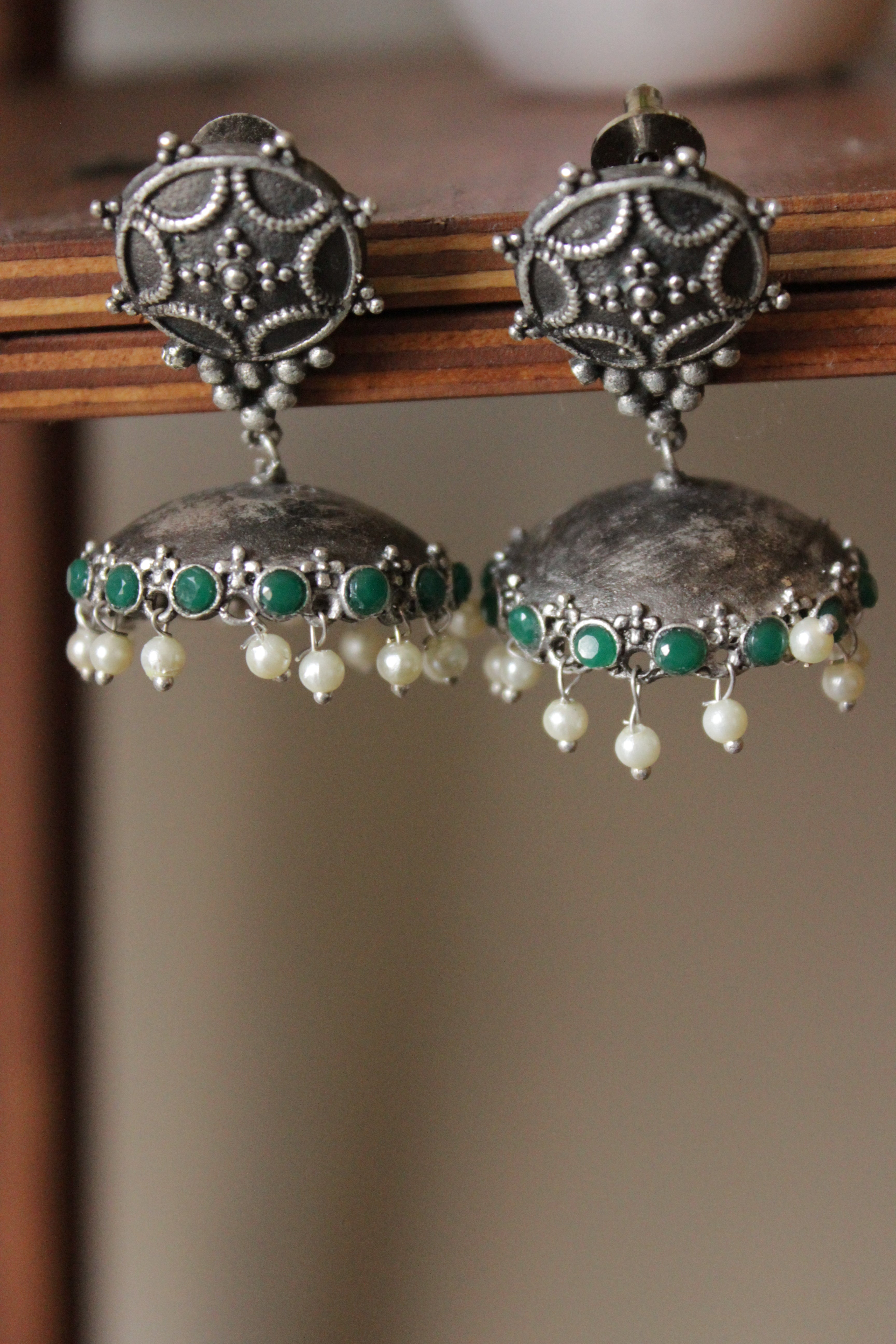 Green Glass Stones Embedded Premium Oxidised Finish Jhumka Earrings Embellished with White Beads