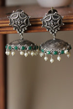 Load image into Gallery viewer, Green Glass Stones Embedded Premium Oxidised Finish Jhumka Earrings Embellished with White Beads
