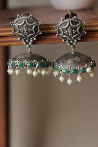 Green Glass Stones Embedded Premium Oxidised Finish Jhumka Earrings Embellished with White Beads