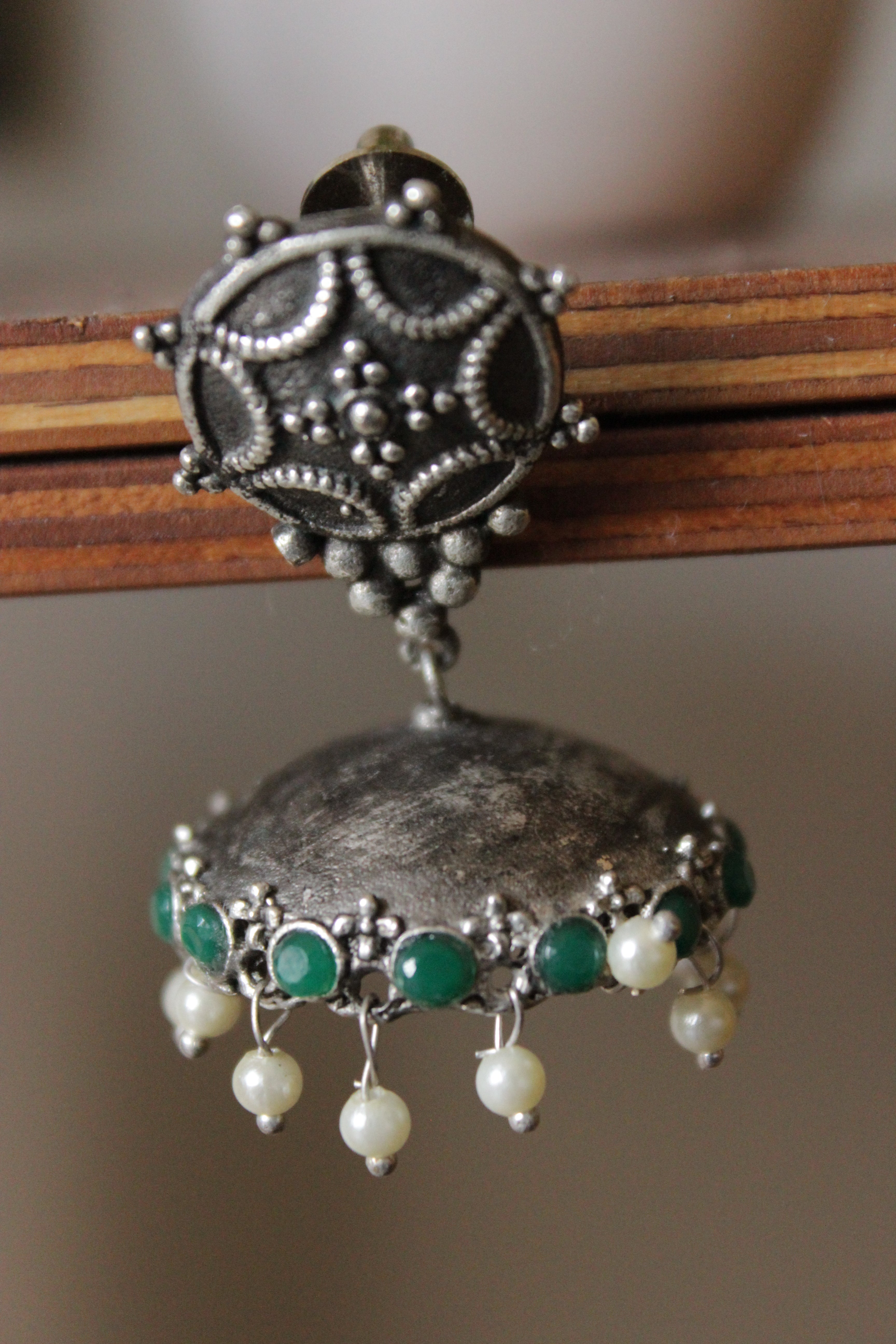 Green Glass Stones Embedded Premium Oxidised Finish Jhumka Earrings Embellished with White Beads