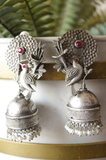 Load image into Gallery viewer, Red Stones Embedded Silver Finish Peacock Motif Statement Jhumka Earrings Accentuated with White Beads
